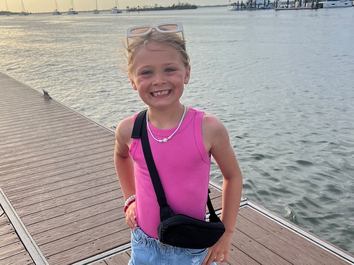 Sloane, all smiles on a dock in her favorite colors