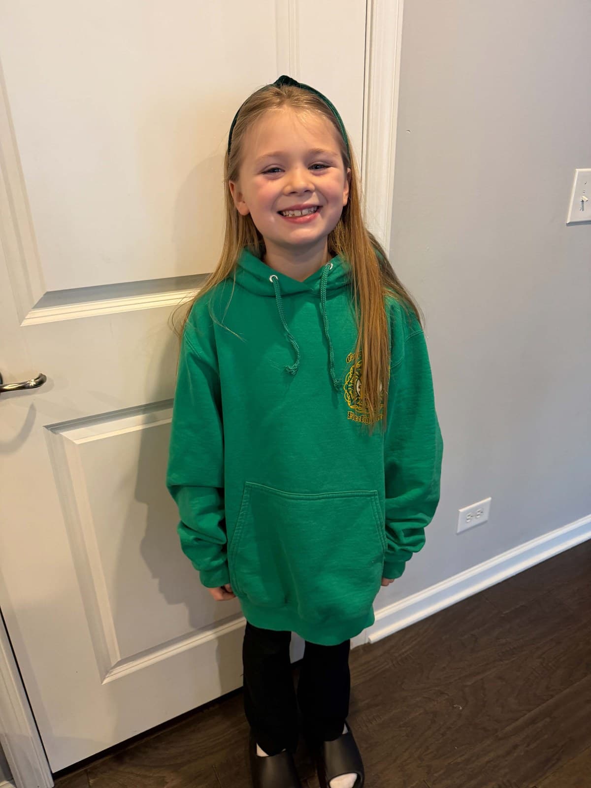 Sloane at home in a green hoodie